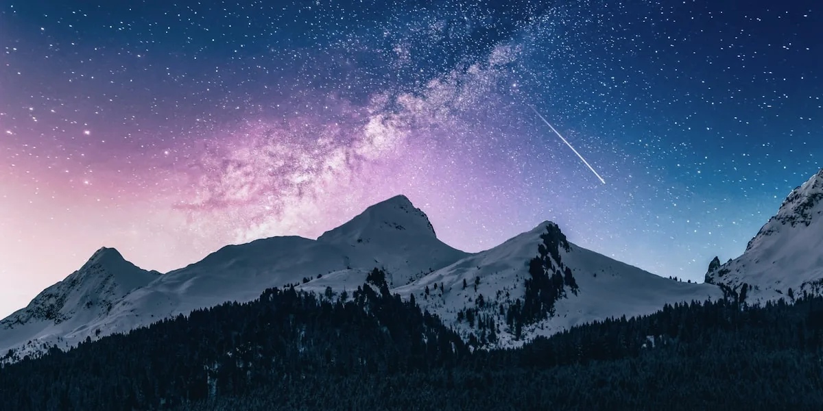 Pessoa numa montanha a olhar para um céu estrelado